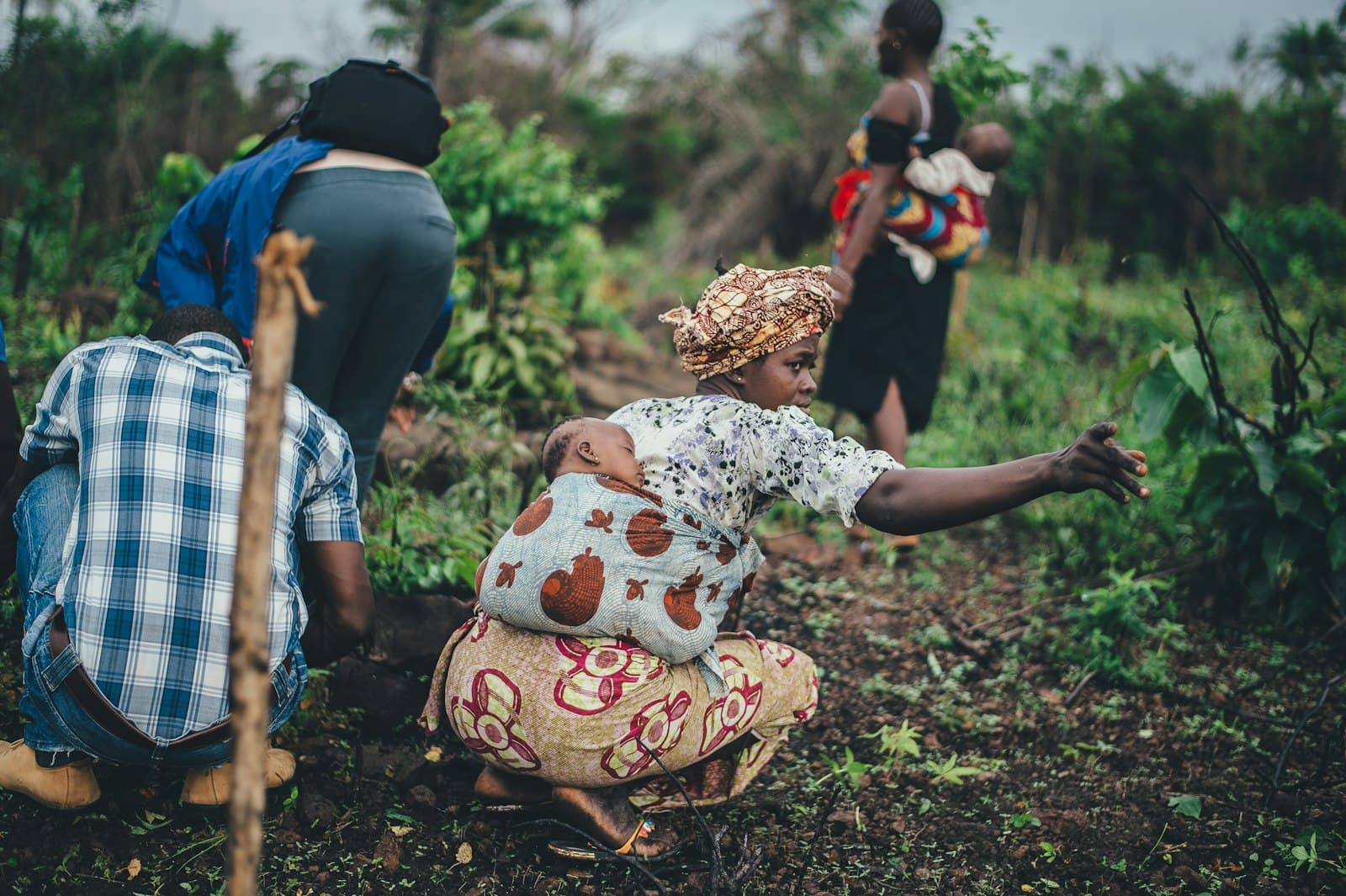 Agricultrice plantant dans son champ, son enfant sur le dos