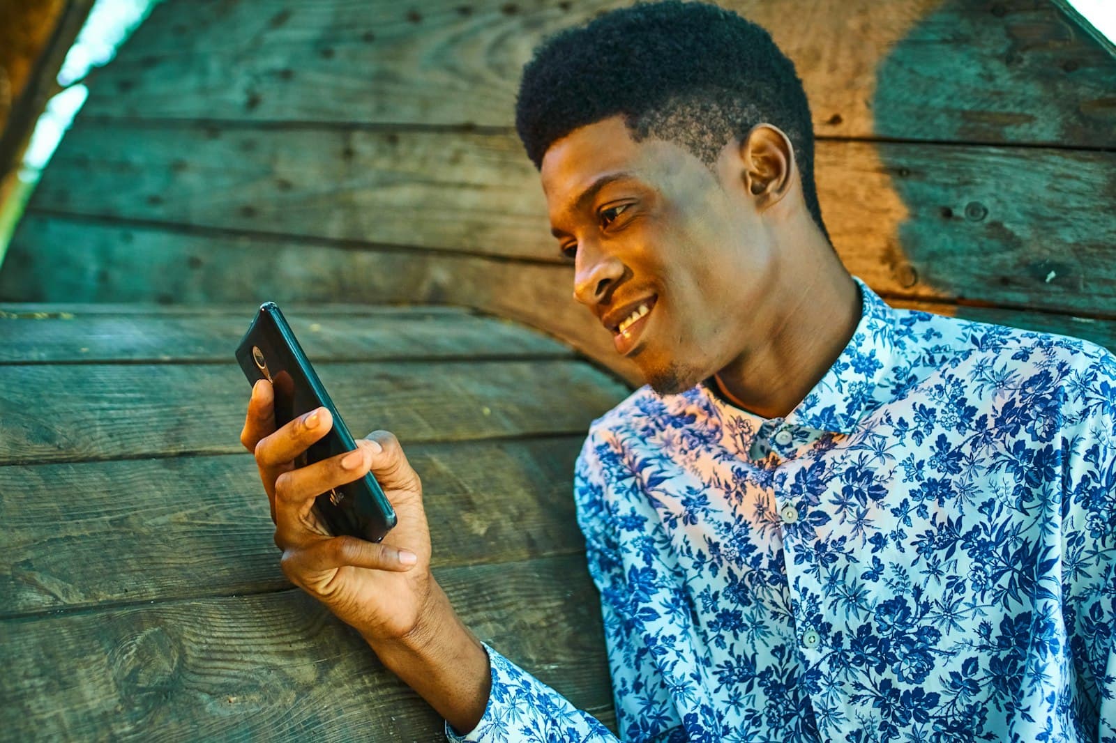 Jeune homme souriant regardant son téléphone